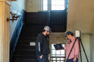 Two staff members standing in the stairwell of the Aiken-Rhett House Museum performing laser scanning